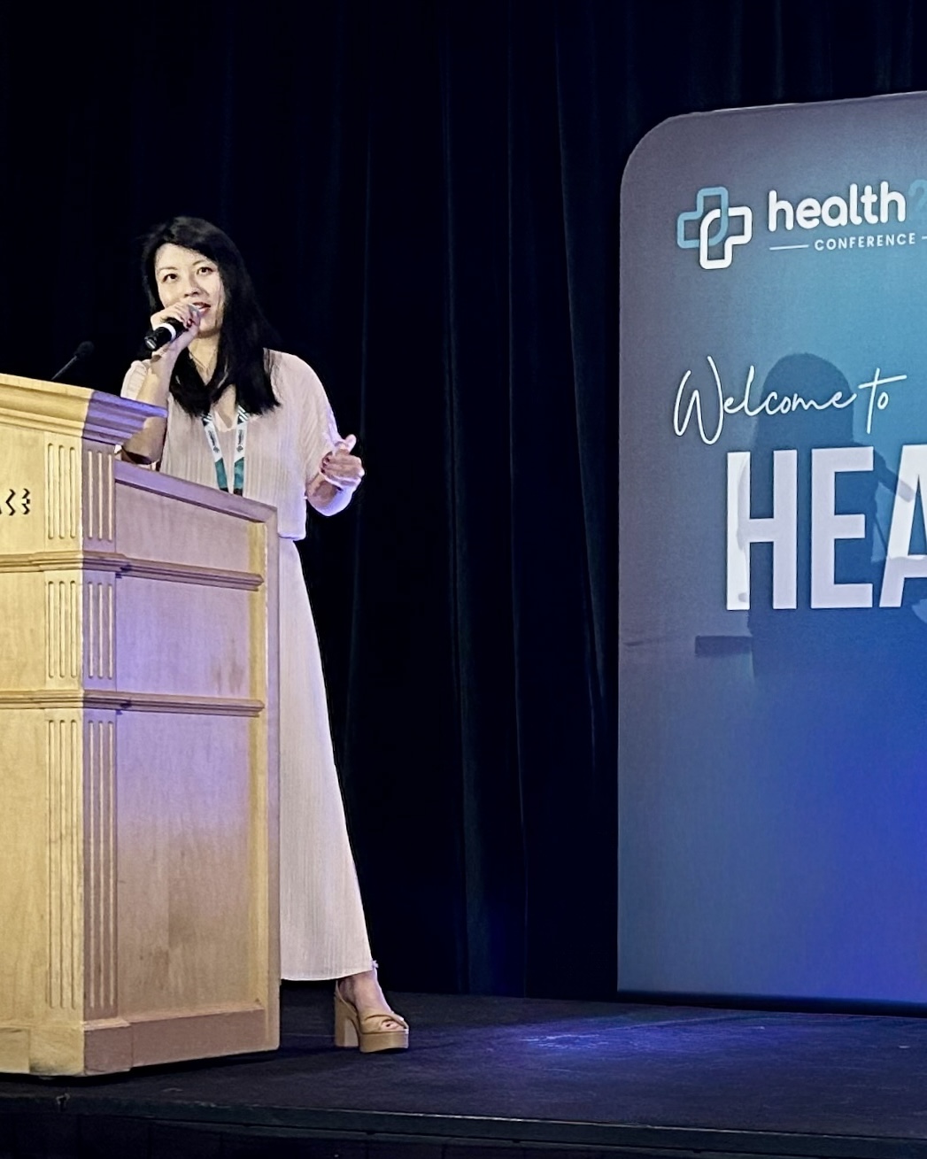 Leslie Chen speaking on stage at a health conference